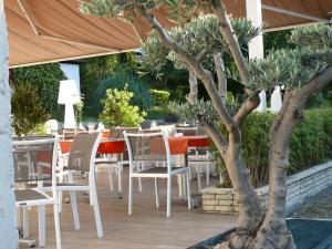 a restaurant with a table and chairs and a tree at Les Criquets Hôtel & Spa in Blanquefort