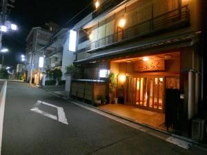 een lege straat 's nachts met een gebouw bij Ryokan Kyoraku in Kyoto