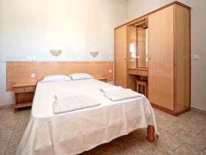 a bedroom with a large white bed and a wooden cabinet at Maria Apartments in Sidari