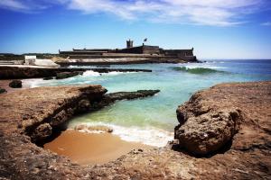 una spiaggia con rocce e l'oceano e un faro di Carcavelos Beach Apartment a Cascais
