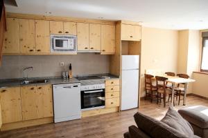 a kitchen with white appliances and a table with chairs at Apartamentos SNÖ Mont Romies in Salardú