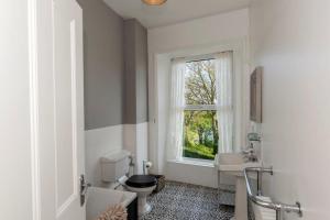 a bathroom with a toilet and a sink and a window at Baie Mooar House, Boutique B&B in Ramsey