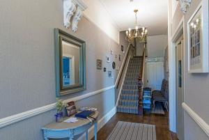a hallway with a staircase with a mirror and a table at Baie Mooar House, Boutique B&B in Ramsey
