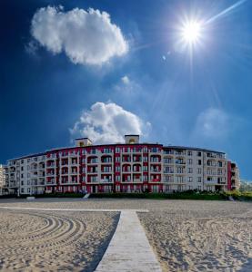 duży czerwono-biały budynek na plaży w obiekcie Primea Beach Residence w Carewie