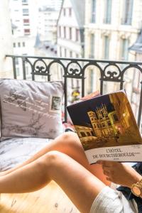 une femme assise sur un lit en train de lire un livre dans l'établissement charming city center flat, à Rouen