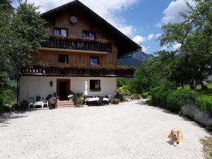 un perro sentado frente a una casa en Haus Galler - Urlaub am Bauernhof en Bad Aussee