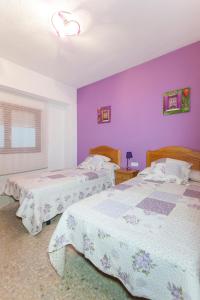 two beds in a bedroom with purple walls at Prado in Peniscola