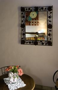 a table with a vase of flowers and a mirror at Pousada Villaggio Assis in Ilhabela