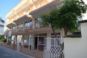 un bâtiment avec une clôture blanche et un arbre dans l'établissement Hotel Eva, à Ravda