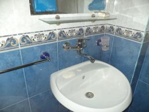 a white sink in a blue tiled bathroom at Guest house Stoyanovi in Chernomorets