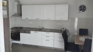a kitchen with white cabinets and a sink and a table at Apartman Zoja in Mali Lošinj