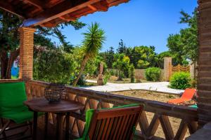 eine Terrasse mit einem Tisch und Stühlen auf einem Zaun in der Unterkunft Porto Gerakas Villas in Vasilikos