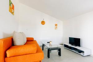 sala de estar con silla naranja y TV en Apartments Luce, en Zadar