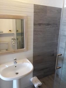 a bathroom with a sink and a shower with a mirror at Tropical Sunset Beach Apartment Hotel in Saint James