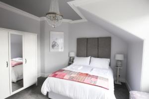 a bedroom with a white bed and a chandelier at High Terrace Apartment in Boat of Garten