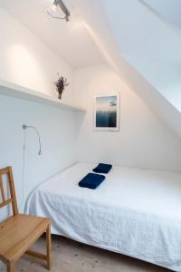 a white bedroom with a bed and a wooden chair at Pedersminde Guesthouse in Fredensborg