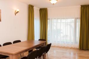 a dining room with a wooden table and green curtains at Complex Adal in Eforie Nord