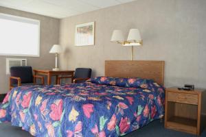 a hotel room with a bed with a colorful bedspread at Bluffs Inn in Bessemer