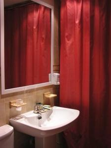 a bathroom with a sink and a red shower curtain at Arcas de Agua in Arcas