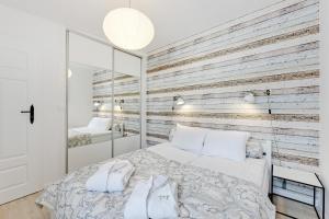 a bedroom with a wooden accent wall with a bed at Lion Apartments - La Playa in Sopot