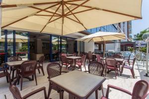 un patio al aire libre con mesas, sillas y sombrillas en Hotel Miramare, en Gatteo a Mare
