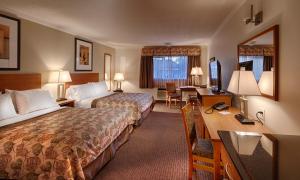 a hotel room with two beds and a desk at Canalta Jurassic in Drumheller