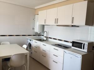 a kitchen with white cabinets and a sink and a microwave at Apartamento frente al mar in San Pedro