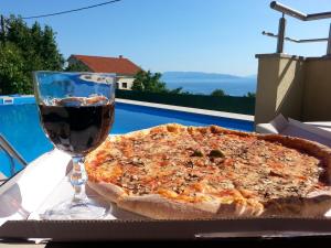 a pizza and a glass of wine on a table at Casa Bellavista in Rijeka