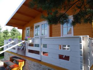 a front porch of a house with a white fence at Lesny domek in Międzyzdroje +7 photos