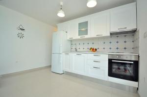 uma cozinha com armários brancos e um frigorífico em Apartment Sunset em Primošten