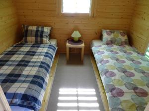 two beds in a wooden cabin with a table at Lesny domek in Międzyzdroje