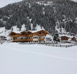 a large building in the snow in front of a mountain at Landhaus Alpensonne in Neustift im Stubaital