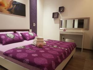 sypialnia z łóżkiem z fioletową pościelą i biurkiem w obiekcie Apartment Adis w Szybeniku