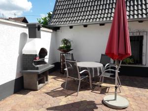 una mesa con sillas y una sombrilla roja en el patio en Ferienhaus am Erlenbach, en Oberhausen