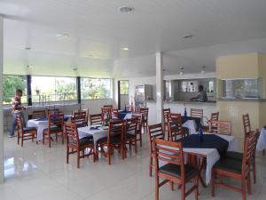 a restaurant with tables and chairs and a person in the background at Hotel SESI Valença in Valença