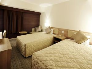 Habitación de hotel con 2 camas y mesa en UNIZO INN Shin-Osaka en Osaka