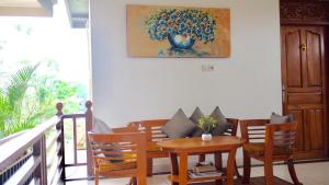 une salle à manger avec une table, des chaises et un tableau dans l'établissement Ramaniya House, à Ubud