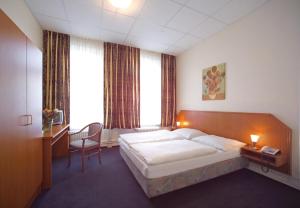 a bedroom with a bed and a desk with a chair at Hotel Terminus am Hauptbahnhof & ZOB in Hamburg