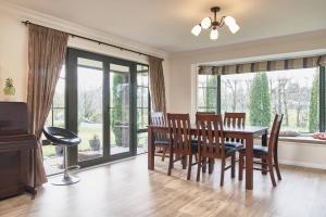 a dining room with a table and chairs and windows at Chester Oaks B&B in West Melton