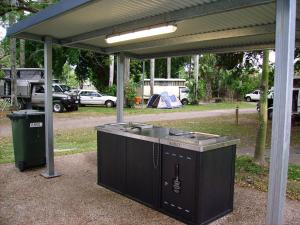 a kitchen area with a refrigerator, stove, and trash can at NRMA Cairns Holiday Park in Cairns