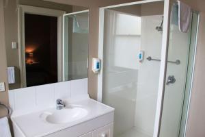 a bathroom with a shower, sink, and mirror at Sporties Hotel in Launceston