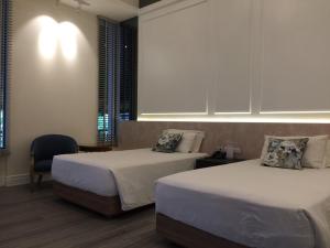 a hotel room with two beds and a chair at iuDia Hotel in Phra Nakhon Si Ayutthaya