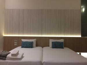 two beds with blue pillows sitting next to each other at iuDia Hotel in Phra Nakhon Si Ayutthaya