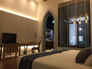 a bedroom with a bed and a desk with a television at iuDia Hotel in Phra Nakhon Si Ayutthaya