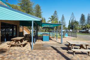 ein Picknickplatz mit Picknicktischen und einem Pool in der Unterkunft NRMA Port Macquarie Breakwall Holiday Park in Port Macquarie
