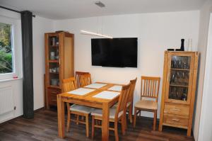 ein Esszimmer mit einem Tisch und Stühlen sowie einem Flachbild-TV in der Unterkunft Haus Tesch in Timmendorfer Strand