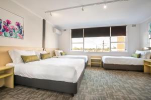 a hotel room with two beds and a window at Nightcap at Hume Hotel in Bankstown