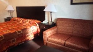 Habitación de hotel con cama y silla en Deer Field Inn, en Osceola