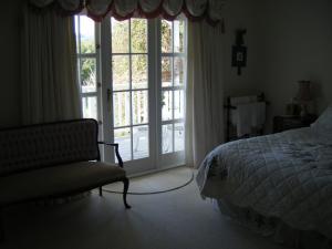 a bedroom with a bed and a chair and sliding doors at Country Lane Homestay B&b in Palmerston North