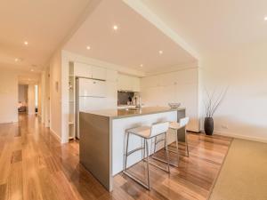 a kitchen with white cabinets and a bar with stools at 9/4 The Esplanade, Cowes - Cscape in Cowes